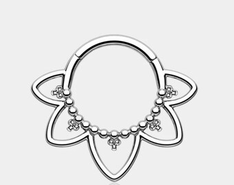 May include: A silver-colored septum ring with a floral design. The ring features a circular shape with a series of small, round beads and decorative elements. The design is symmetrical and detailed, with a polished finish.