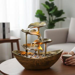 以下が含まれることがあります： 階層的なデザインの装飾的な屋内噴水。 噴水は、小さな石で満たされたブロンズ色のボウルに水が流れ込む、4つの葉の形をした層を備えています。 噴水の高さは約30cmです。