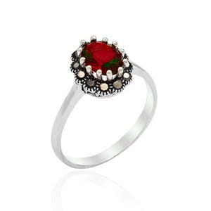 May include: A silver ring featuring an oval, deep red gemstone at the center, surrounded by a halo of smaller, dark stones. The ring's band is a simple, polished silver.