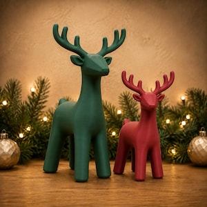 May include: Two standing deer figurines with a smooth, matte finish. The larger deer is dark green, and the smaller deer is dark red. Both figures feature stylised, geometric antlers and a minimalist, solid-coloured body design with four legs.