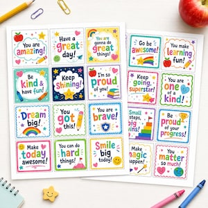 Peut inclure: Deux feuilles d'autocollants carrés avec des phrases motivantes colorées et des illustrations comme des arcs-en-ciel, des étoiles, des cœurs et des crayons. Le texte inclut You are amazing, Have a great day, Keep Shining et You matter so much.