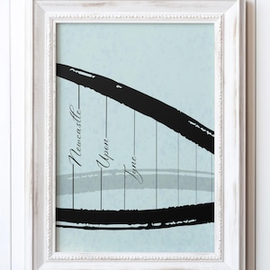 May include: Framed art print featuring a stylized black illustration of a bridge against a light blue background. The text "Newcastle Upon Tyne" is written vertically on the left side of the image. The frame is white.