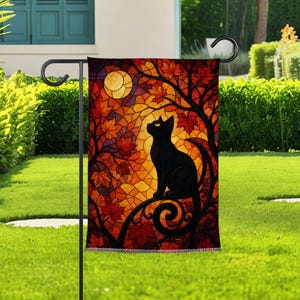 Könnte beinhalten: Eine rechteckige Gartenflagge mit einer Illustration im Buntglasstil, die eine schwarze Katze auf einem geschwungenen Ast zeigt. Der Hintergrund zeigt eine lebendige Herbstszene mit orangefarbenen und roten Ahornblättern und einem gelben Mond.