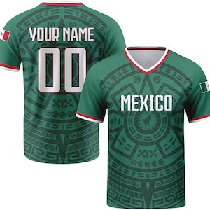 May include: A green short-sleeved V-neck jersey featuring a dark green Aztec-inspired pattern. The front displays the text MEXICO in white, while the back shows the text YOUR NAME and the number 00. Both sleeves feature a small Mexican flag patch.