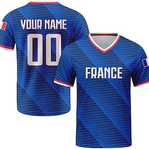 May include: A blue V-neck jersey featuring a diagonal dot pattern, white trim, and the text FRANCE on the front. The back displays the text YOUR NAME above the number 00. Both sleeves feature a small rectangular French flag patch.