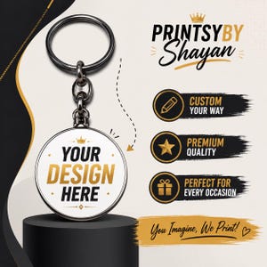 May include: A round metal keychain with a white center featuring the text YOUR DESIGN HERE in black and gold. The keychain has a dark metallic ring and connector. Text on the right includes PRINTSYBY SHAYAN, CUSTOM YOUR WAY, PREMIUM QUALITY, and PERFECT FOR EVERY OCCASION.