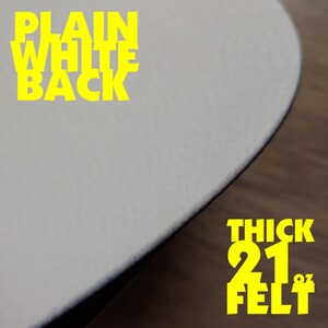 May include: Close-up of a thick, white felt circle with the text "PLAIN WHITE BACK" in yellow at the top and "THICK 21" FELT" in yellow at the bottom.