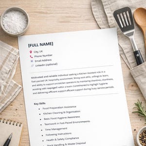 May include: A white resume with text, including "Kitchen Assistant" and key skills like "Food Preparation Assistance." The resume is on a wooden surface with kitchen utensils, spices, and a notepad.