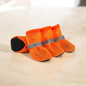 Puede incluir: Cuatro botas de malla naranja brillante para perros, con suelas negras y correas grises reflectantes. Las botas est&aacute;n dise&ntilde;adas para proteger las patas de un perro. Est&aacute;n hechas de un material de malla transpirable.