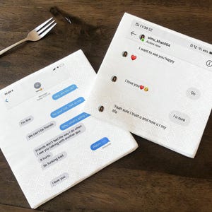 Op de afbeelding: Twee witte papieren servetten bedrukt met sms-gesprekken. Eén servet toont berichten als "Het gaat goed" en "Ik hou van je". Het andere servet toont berichten als "Ik wil je graag gelukkig zien" en "Ik hou van je."