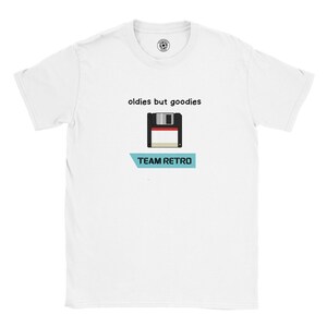 Könnte beinhalten: Weißes T-Shirt mit einem Retro-Disketten-Grafikdesign, dem Text "oldies but goodies" darüber und "TEAM RETRO" darunter. Das Design umfasst Schwarz, Rot, Weiß und Hellblau. Ein klassisches und nostalgisches Design.