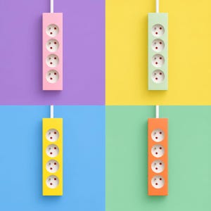 May include: Four rectangular power strips with four outlets each, displayed in a grid. The strips are pink, light green, yellow, and orange, each featuring a white power cord extending from the top against matching coloured backgrounds.