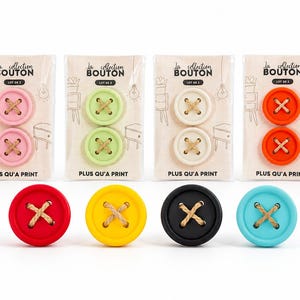 Puede incluir: Una colección de botones coloridos y grandes en varios tonos, incluyendo rosa, verde, blanco y naranja, con costuras cruzadas de hilo de color natural. El texto "La collection BOUTON" y "PLUS QU'A PRINT" son visibles.
