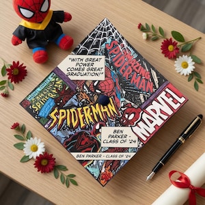 Op de afbeelding: Een Spider-Man thema afstudeerhoed met stripboekkunst en de tekst "With great power comes great graduation!" en "Ben Parker - Class of '24". Een Spider-Man knuffel, bloemen, een pen en een diploma zijn ook aanwezig.