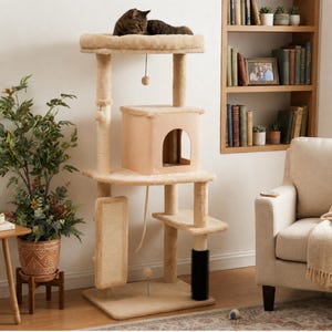 May include: A beige multi-level cat tree featuring a top circular perch with a resting cat, a central enclosed cubby house, a rectangular sisal scratching pad, a black cylindrical grooming brush, and several hanging toy balls on strings.