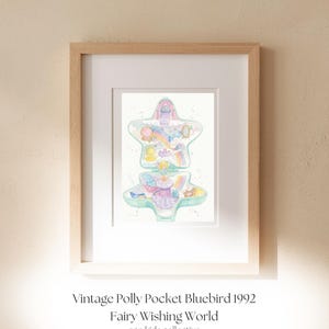 May include: A framed print featuring a watercolour illustration of a star-shaped Polly Pocket toy. The artwork displays pastel colours, rainbows, and miniature figures. Below the image, the text reads: Vintage Polly Pocket Bluebird 1992 Fairy Wishing World eco kids collective.