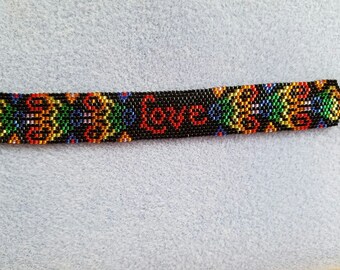 May include: A black beaded bracelet with a colorful pattern and the word "Love" in red beads.