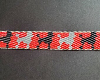 May include: A red, white, and black beaded bracelet with a repeating pattern of poodle silhouettes.