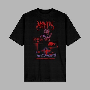 May include: Black t-shirt featuring the word "MANDY" in red gothic lettering above a graphic of a person holding a weapon. Below the graphic are three red rectangles with images and the text "A STORY OF MELANCHOLIC INSANITY."