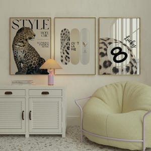 May include: Three framed art prints with gold frames. One features a leopard, another has skateboards, and the third displays a pool ball with the number 8. The prints are displayed above a white cabinet and a yellow beanbag chair.