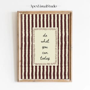 Peut inclure: Une affiche murale encadr&eacute;e pr&eacute;sentant un rectangle central cr&egrave;me avec le texte 'do what you can today' en police manuscrite sombre, entour&eacute; d'une bordure de tirets, sur un fond de rayures verticales textur&eacute;es brun fonc&eacute;.