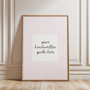 May include: A rectangular framed print featuring a light pink and white vertical striped background with a central white square containing the dark gray handwritten text that reads your handwritten quote here in a casual script font style.