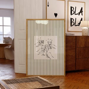 Puede incluir: Una pieza de arte mural rectangular enmarcada con un fondo de rayas verticales en color verde salvia claro y blanco. En el centro, un cuadrado blanco contiene un dibujo lineal negro de cuatro manos sosteniendo copas de cóctel en un brindis.
