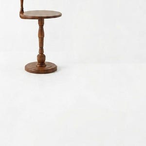 May include: A floor lamp with a brown wooden stand and a circular side table integrated into the base. The lamp features a tall, turned wooden post and a pleated, light tan fabric lampshade. The base is round and sturdy, supporting the table.