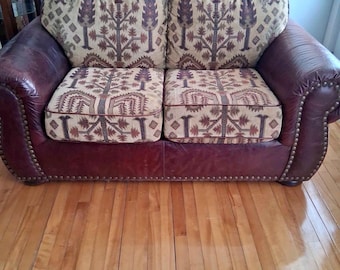 Sofa dwuosobowa ze skóry w stylu południowo-zachodnim, poduszki z gobelinu, lamówka z ćwiekami, rustykalny wystrój domku letniskowego