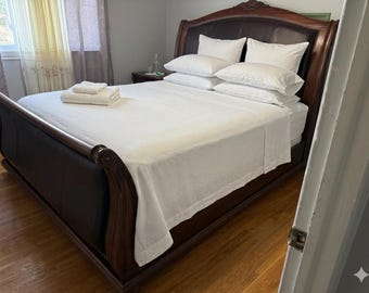 Cama de lujo King con cabecero estilo trineo, incrustaciones de cuero y mesitas de noche a juego de madera de raíz.