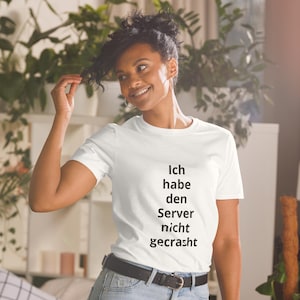 Könnte beinhalten: Ein weißes T-Shirt mit dem deutschen Text "Ich habe den Server nicht gecrasht" in Schwarz. Das T-Shirt wird von einer Person mit dunklen Haaren getragen und mit einer blauen Jeans und einem schwarzen Gürtel kombiniert.