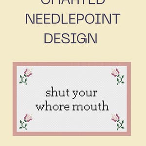 May include: A charted needlepoint design featuring the text 'shut your whore mouth' in black cross-stitch lettering. The rectangular pattern is bordered in pink and decorated with four small pink and green floral motifs in the corners.