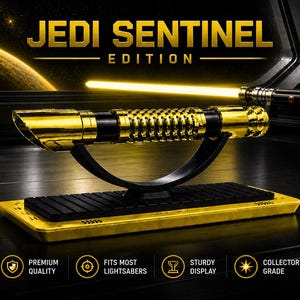 Pode incluir: Um sabre de luz dourado com uma pega preta &eacute; exibido em um suporte preto. O sabre de luz &eacute; rotulado como "Jedi Sentinel Edition". O suporte est&aacute; sobre uma base dourada. A imagem tamb&eacute;m inclui &iacute;cones de qualidade premium, exibi&ccedil;&atilde;o resistente e grau de colecionador.