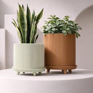 Puede incluir: Un juego de tres tazas de cerámica con un acabado mate moteado. Las tazas son de color crema, gris claro y gris oscuro. Cada taza tiene un diseño simple y minimalista.