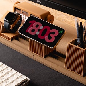 May include: A desk organizer made of corrugated cardboard, holding a smartphone displaying the time 18:03, a smartwatch, pens, and a flip clock. The organizer is brown and sits on a desk with a keyboard.