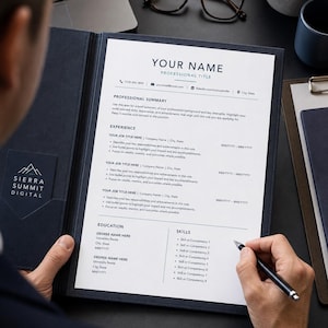 May include: A navy blue resume folder with a resume inside. The resume has the text "YOUR NAME PROFESSIONAL TITLE" at the top. A hand is holding a pen, ready to write on the resume. The Sierra Summit Digital logo is visible.
