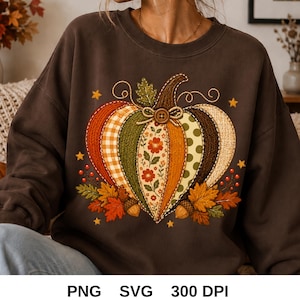 Könnte beinhalten: Ein dunkelbraunes Langarm-Sweatshirt mit einer großen zentralen Grafik eines Kürbisses, der aus verschiedenen gemusterten Segmenten wie Karos, Blumen und Punkten besteht, verziert mit einem kleinen Knopf, Herbstblättern und Eicheln.