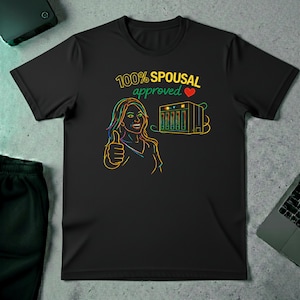 May include: Black t-shirt with a neon graphic. The graphic shows a woman giving a thumbs up, a server rack, and the text "100% Spousal Approved" with a heart symbol. The design is outlined in yellow, green, and blue.