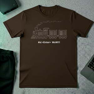 May include: A brown t-shirt featuring a white line drawing of a train with the text "#sl <Enter> WoW!!!". The train design includes a locomotive and several train cars. The shirt is made of a soft material.