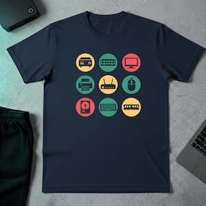 Op de afbeelding: Marineblauw T-shirt met een raster van computerpictogrammen in gele, groene en rode cirkels. De pictogrammen omvatten een computer, RAM, monitor, printer, router, muis, harde schijf, toetsenbord en RAM.
