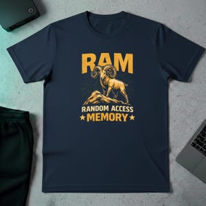 May include: Navy blue t-shirt with a graphic of a ram standing on a mountain, with the word "RAM" above it in yellow block letters. Below the ram is the text "RANDOM ACCESS MEMORY" with star accents.