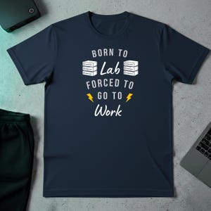 May include: Navy blue t-shirt with the text "BORN TO Lab FORCED TO GO TO Work" in white. The design includes two stacks of servers and lightning bolts. A casual tee for lab enthusiasts.