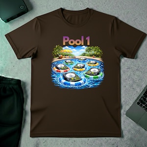 Puede incluir: Camiseta marrón con un diseño gráfico colorido de una escena de piscina con dispositivos flotantes en flotadores. El texto "Pool 1" está encima de la piscina. Palmeras, una sombrilla amarilla y agua azul completan el diseño.