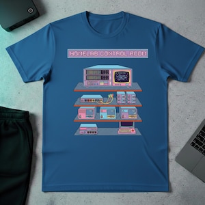 May include: Blue t-shirt featuring a "HOMELAB CONTROL ROOM" graphic. The design shows retro-style computer equipment on shelves, in pink, blue, and yellow. The text "HOMELAB CONTROL ROOM" is in a rectangular box.