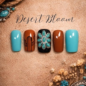 Puede incluir: Un conjunto de cinco uñas artificiales con temática desértica. Las uñas están pintadas en turquesa, marrón y negro. Una uña presenta un diseño de cactus, y otra tiene un diseño de flor turquesa. El texto "Desert Bloom" está escrito en cursiva.