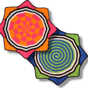 Könnte beinhalten: Zwei sternförmige Häkelarbeiten in leuchtenden Farben. Eine hat ein rosa, orange und weiß kariertes Muster, die andere ein blaues, grünes und weißes Spiraldesign. Beide haben schwarz-weiße Ränder und zeigen eine helle, handgefertigte Ästhetik.