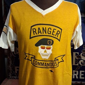 May include: A white ceramic mug with a black handle and the text "But First, Coffee" in a bold, black font. The mug is set against a blurred background, suggesting a cozy setting.