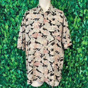 May include: Short-sleeved button-down shirt with a repeating pattern of stylized fish in shades of gray, pink, and beige on a black background. The shirt has a classic collar and buttoned front. The shirt is displayed on a mannequin.