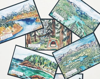 May include: A collection of watercolor art prints featuring various national park landscapes. Each print showcases a different park, including Grand Teton, Redwood, and Glacier Bay, with vibrant colors and detailed scenery. The prints have black borders.