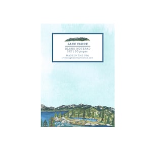 May include: A blank notepad with a watercolor illustration of Lake Tahoe. The notepad features a blue border with the text "LAKE TAHOE BLANK NOTEPAD 5X7 | 50 pages MADE IN THE USA". The bottom of the notepad has a landscape illustration of the lake and mountains.